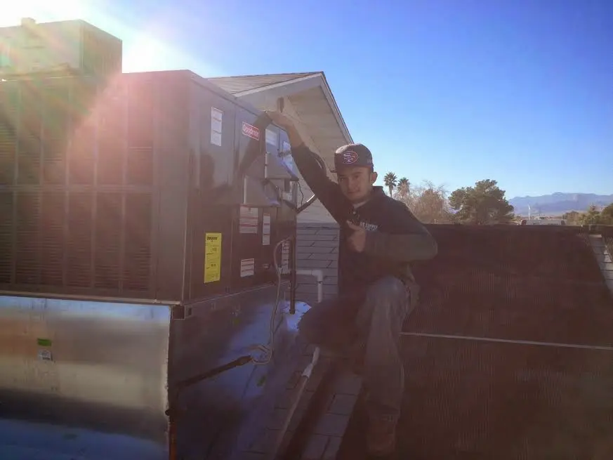 HVAC technician performing AC Tune-Up on a rooftop unit in Winterset
